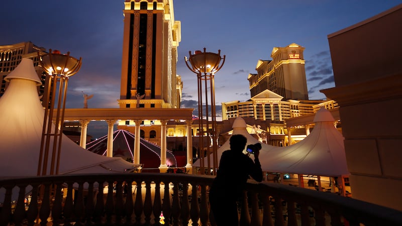 In this Jan. 12, 2015, file photo, a man takes pictures of Caesars Palace hotel and casino in...