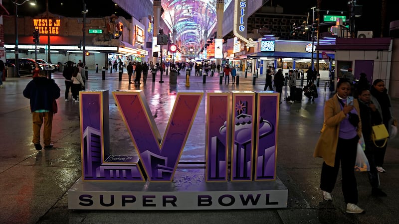 People walk past a sign for Super Bowl 58 at the Fremont Street Experience Tuesday, Feb. 6,...