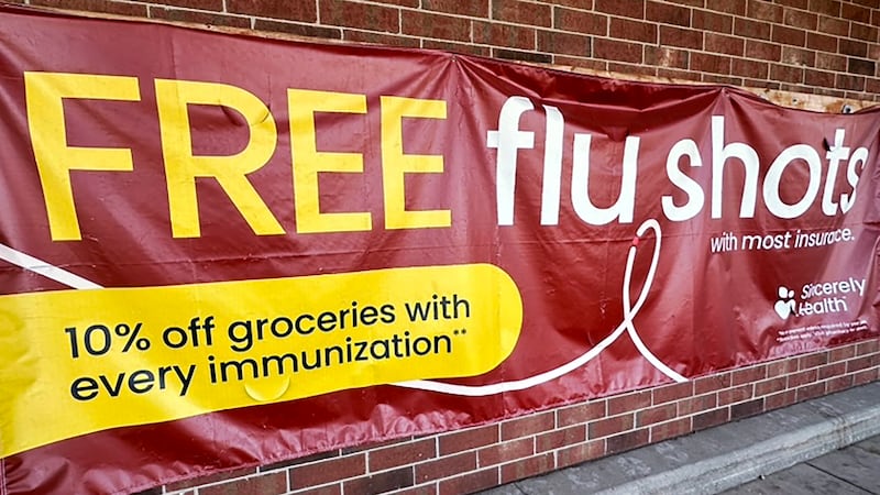 FILE - A sign for flu vaccination is displayed outside of a grocery store in Glenview, Ill.,...