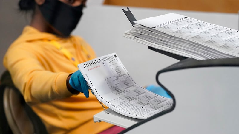 FILE - In this Nov. 5, 2020, file photo a county election worker scans mail-in ballots at a...