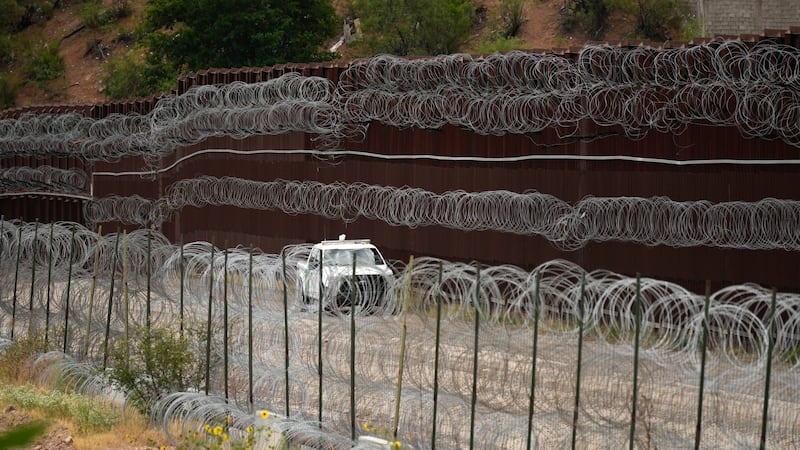 FILE - A vehicle drives along the U.S. side of the US-Mexico border wall in Nogales, Ariz.,...